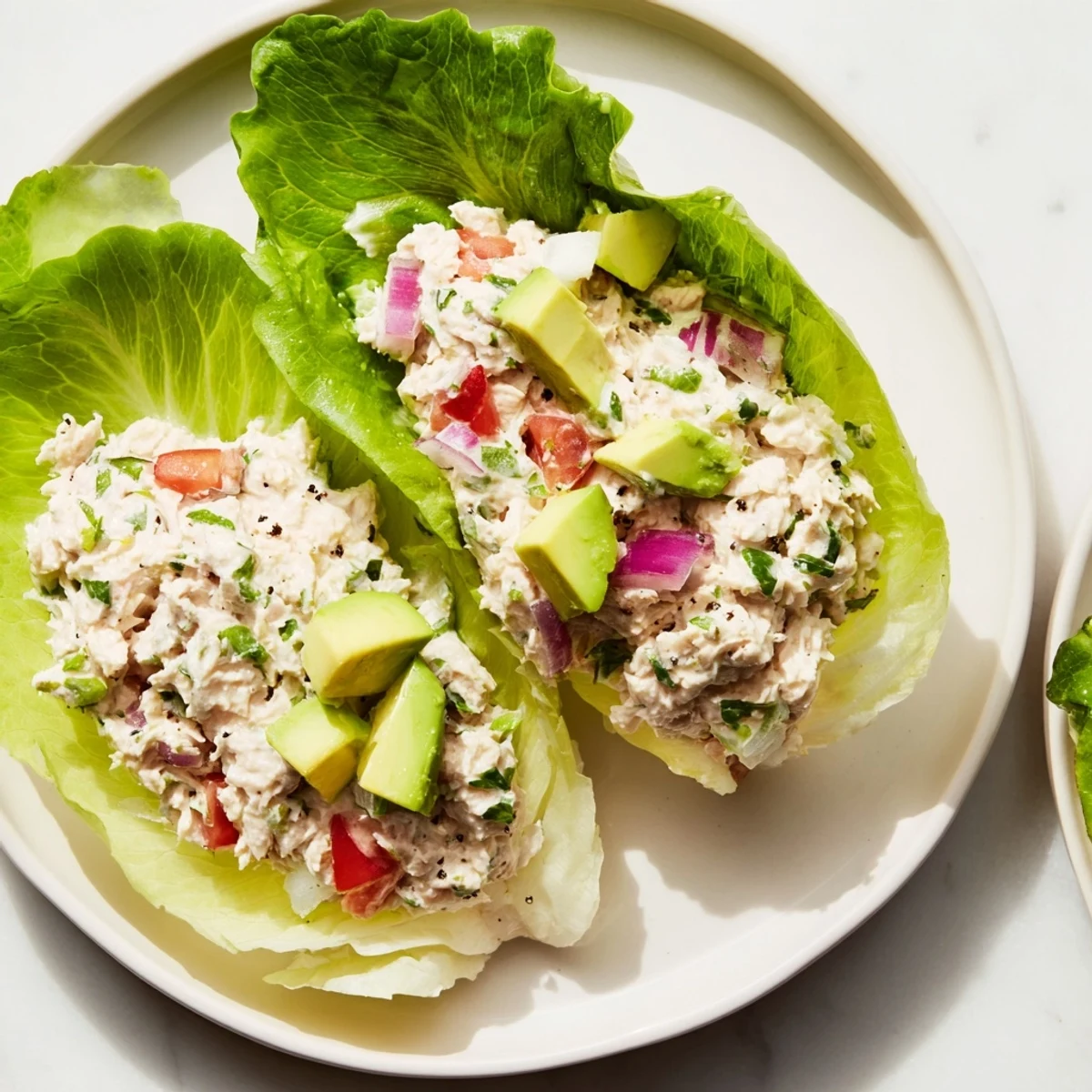 Freshly made tuna salad lettuce wraps, loaded with avocado and tomato, a healthy lunch.