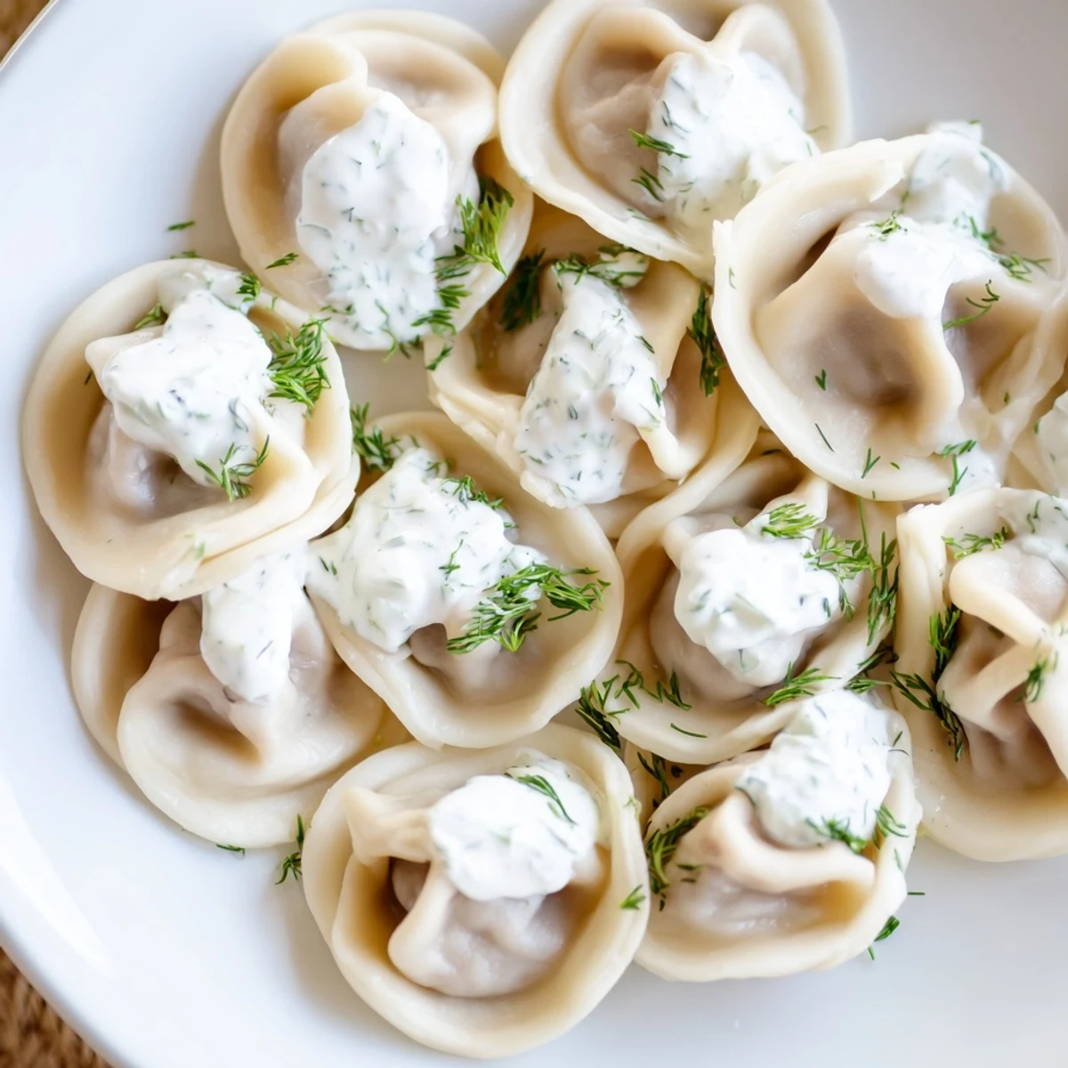Steaming hot Russian pelmeni, tender meat dumplings under a dollop of creamy sour cream.