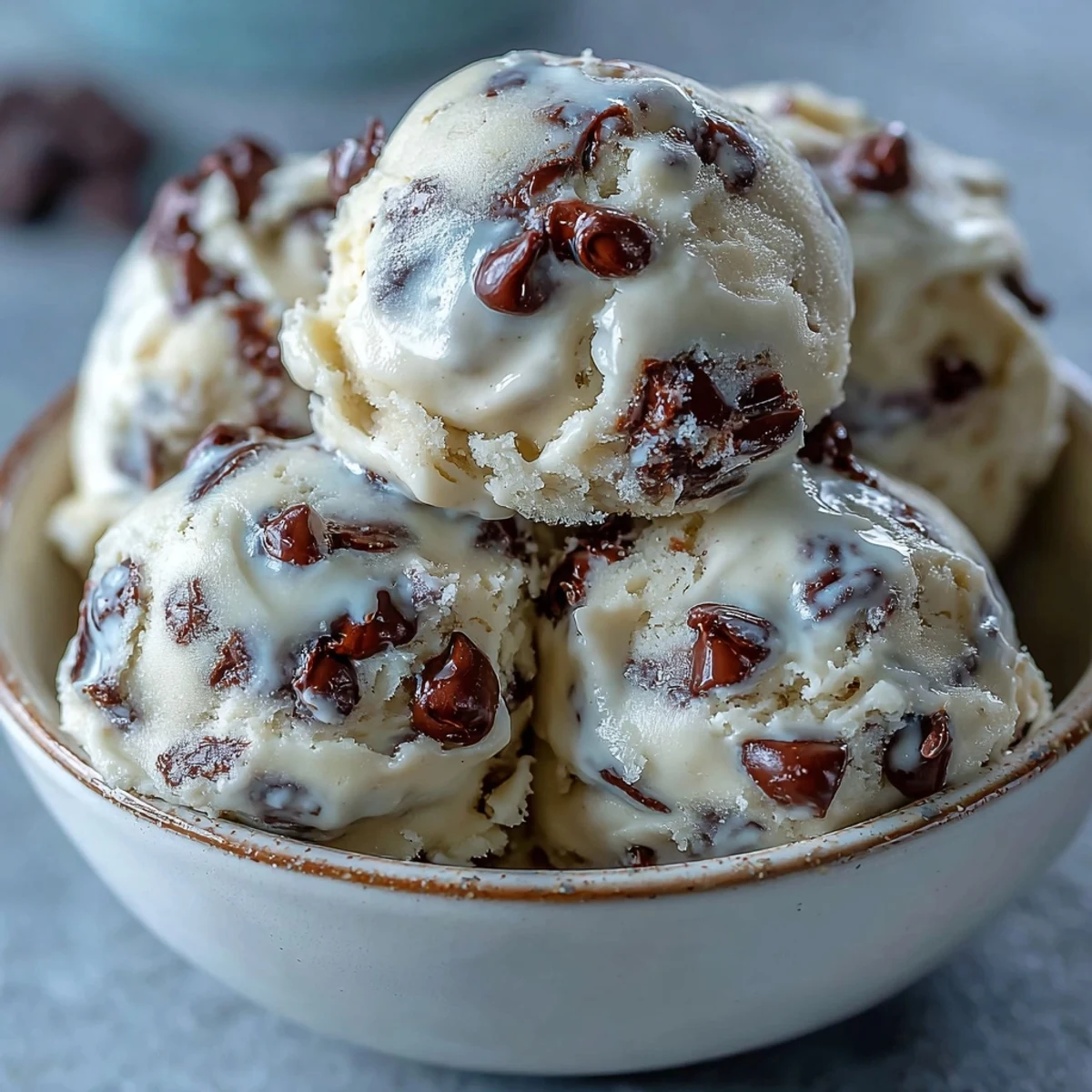 Homemade Greek Yogurt Cookie Dough in a glass bowl with a wooden scoop and chips.
