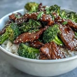 Sizzling beef and broccoli tossed in savory sauce, served warm over jasmine rice with sesame garnish.