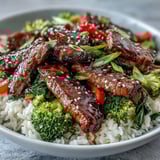 Colorful sautéed carrots, red bell peppers, and broccoli mingle with tender beef in a savory teriyaki glaze over steamed rice.