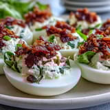 Creamy BLT deviled eggs topped with crispy bacon crumbles and fresh lettuce for a savory appetizer.