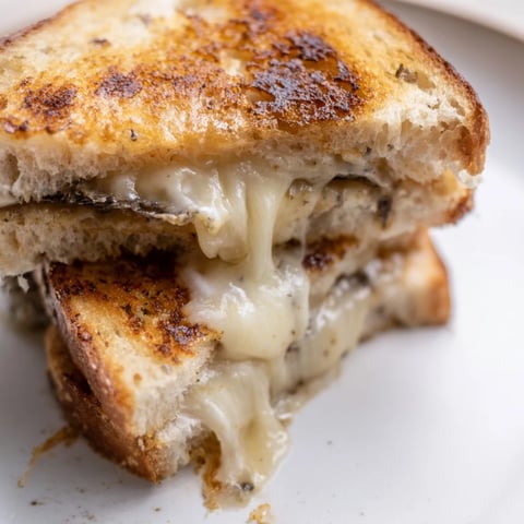 Golden-brown Truffle Grilled Cheese sandwiches with melted Gruyère on crispy sourdough, sliced and ready to serve.