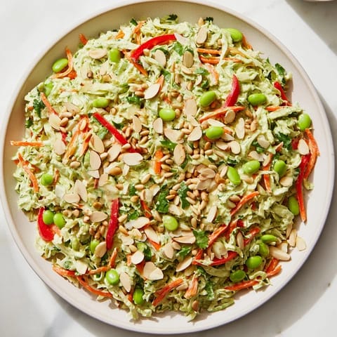 A refreshing bowl of Crunchy Cabbage and Edamame Salad, garnished with toasted almonds and fresh herbs.