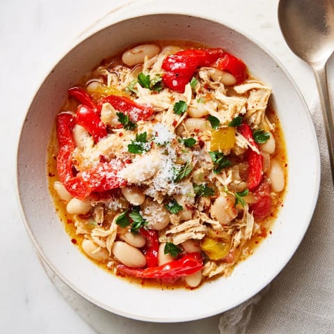 Close up revealing a savory bowl of White Bean and Roasted Red Pepper Chicken, garnished with fresh parsley.