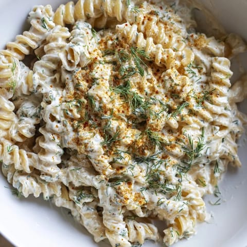 A beautiful bowl of Turkish Yogurt Pasta, with a vibrant red spiced butter drizzle and herbs.