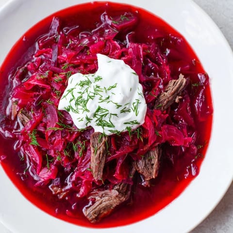 Rustic close-up of hearty Ukrainian Borscht, a beef and vegetable soup with fresh dill sprigs.