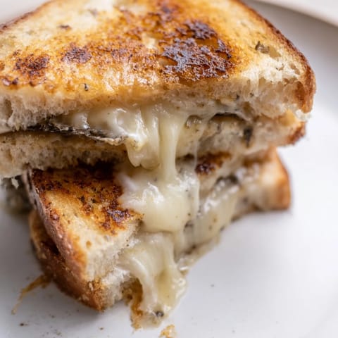 Golden-brown Truffle Grilled Cheese sandwiches with melted Gruyère on crispy sourdough, sliced and ready to serve.