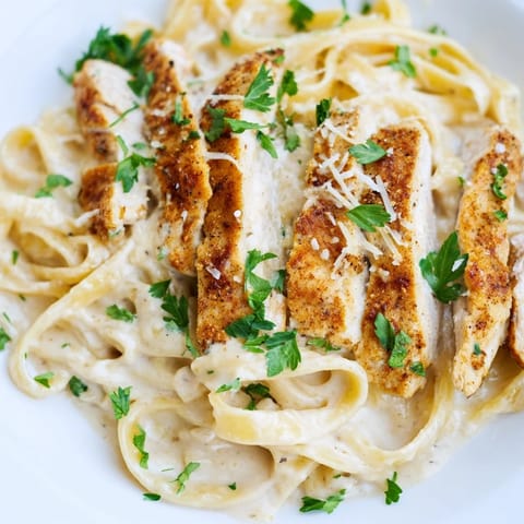 Spicy Cajun Chicken Alfredo garnished with fresh parsley, served with a glass of white wine.