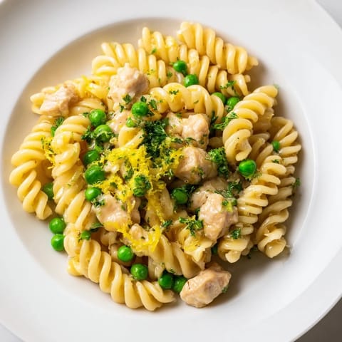 Family-style plate of garlic butter chicken and pea pasta, featuring tender chicken and al dente fusilli tossed with lemon and Parmesan.