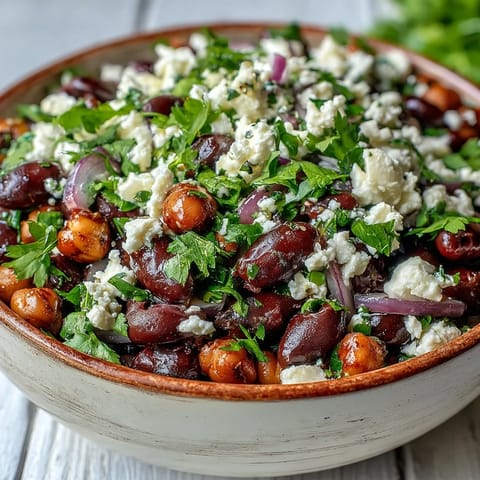 Bright marinated bean salad served cold in a white bowl, topped with thinly sliced red onions for a refreshing lunch or meal-prep dinner.  