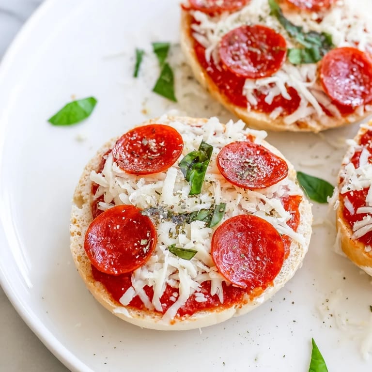 Warm, cheesy mini pepperoni pizza bagels just out of the oven, with crispy pepperoni and herbs.