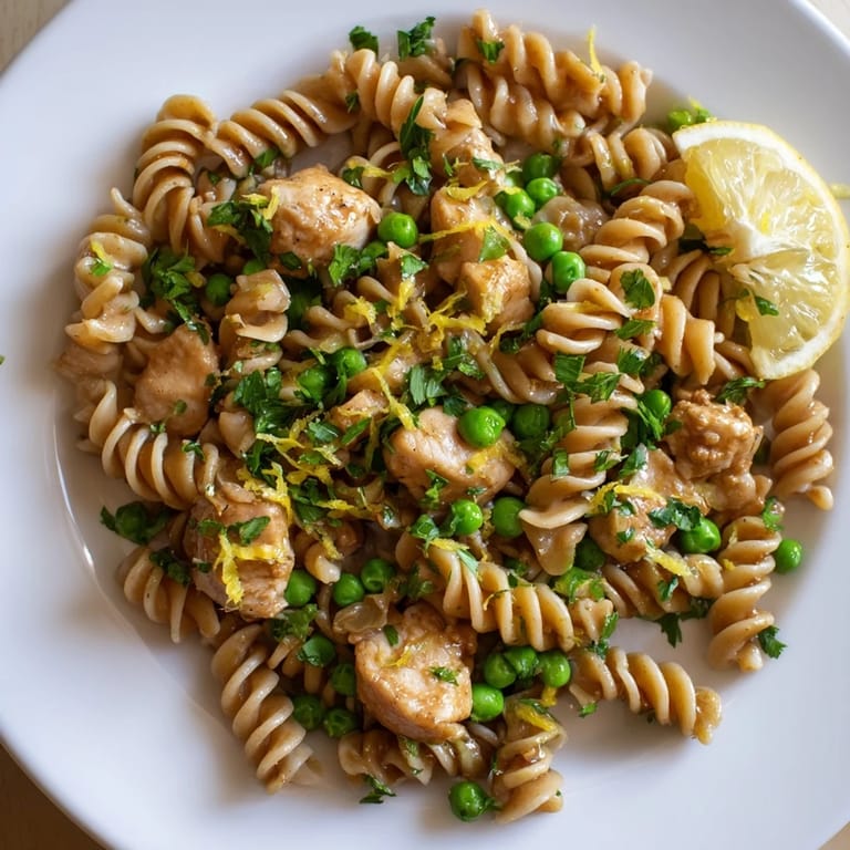 Comforting bowl of garlic butter chicken and pea pasta, steam rising from buttery noodles, sweet peas, and savory chicken ready to serve.