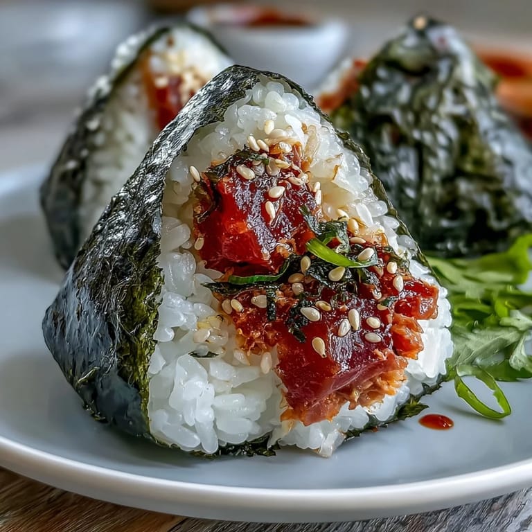 Golden rice balls packed with spicy tuna filling, perfectly shaped and wrapped in nori for a satisfying handheld sushi-inspired treat.  