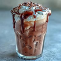 Chocolate cream cold brew with rich, velvety topping and chocolate drizzle, served over ice in a tall glass.